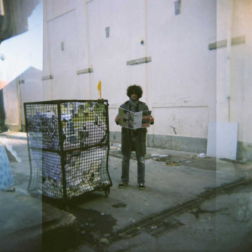 A Man Standing Beside A Trash Bin Cage